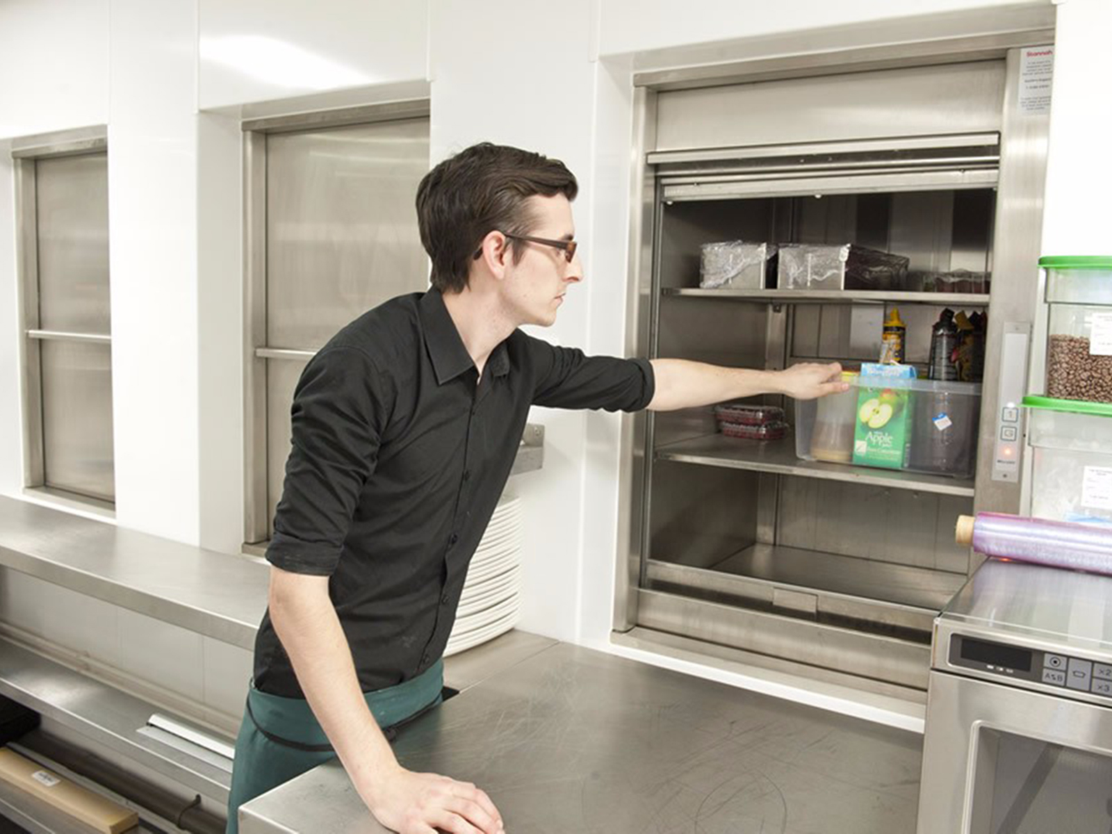 Row of three stainless steel dumb waiters in commercial kitchen
